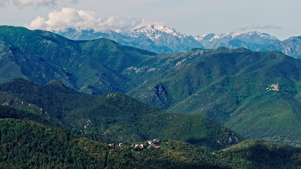 Aerial drone shot over the green lush landscape of inland Corsica, France. High view of the landscape and the mountains in the distance. Summer holidays destination for hikers and mountain lovers