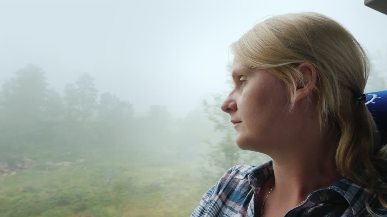 una mujer mira por la ventana de un autobús a un bosque cubierto de niebla espesa que viaja en noruega