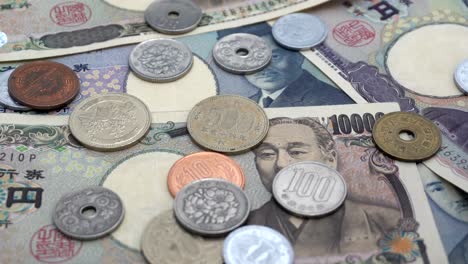 close up of japanese coin yen falling on banknotes 1000 and 10000 yen background with sound