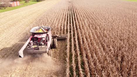Combine-Harvester-At-Work-Gathering-Corn-In-The-Field,-Southeast-Michigan---aerial-drone-shot
