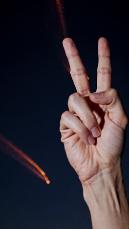 signo de paz contra el cielo nocturno con rastros de luz