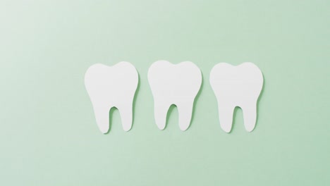 video of three white paper teeth on green background with copy space