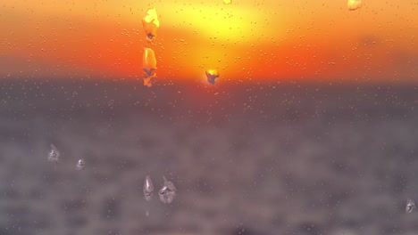 gotas de lluvia en las ventanas, con vistas al atardecer o al amanecer en medio del mar, desdibujan el fondo