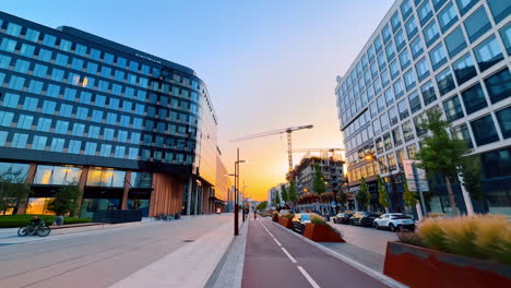 bratislava, slovakia, 2 june 2025: walking by the beautiful modern street with glass high-rises. building is being constructed at backdrop. bratislava, slovakia at sunset