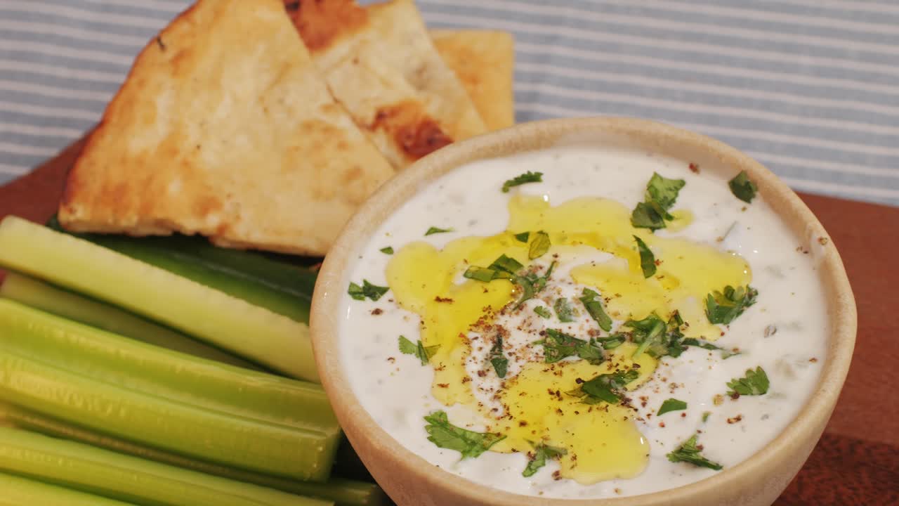 Greek Tzatziki sauce of salted strained yogurt or diluted yogurt mixed with cucumbers and mint, garlic, salt, olive oil on top. High quality 4k footage