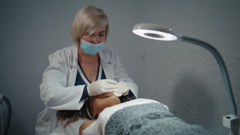 cosmetólogo limpiando la piel facial con almohadillas de algodón después de un tratamiento de belleza en el spa.