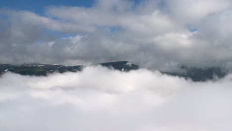 la spessa copertura nuvolosa bianca si muove lentamente mentre sullo sfondo le alte vette dell'hardangervidda in norvegia torreggiano sopra le nuvole