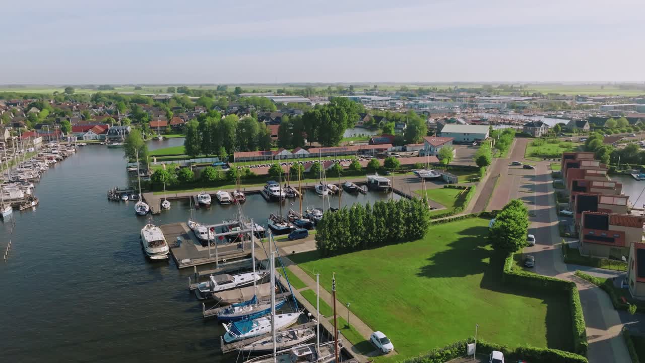 Semi orbit drone shot reveals boats, waterfront homes and open green spaces in Heeg on a sunny day