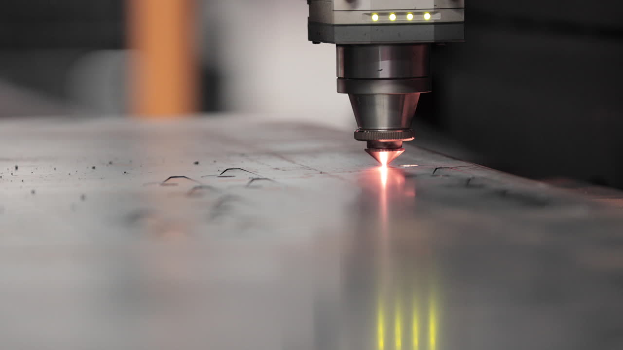 Primo piano della punta di una taglierina laser che taglia una lamiera in acciaio inossidabile con scintille