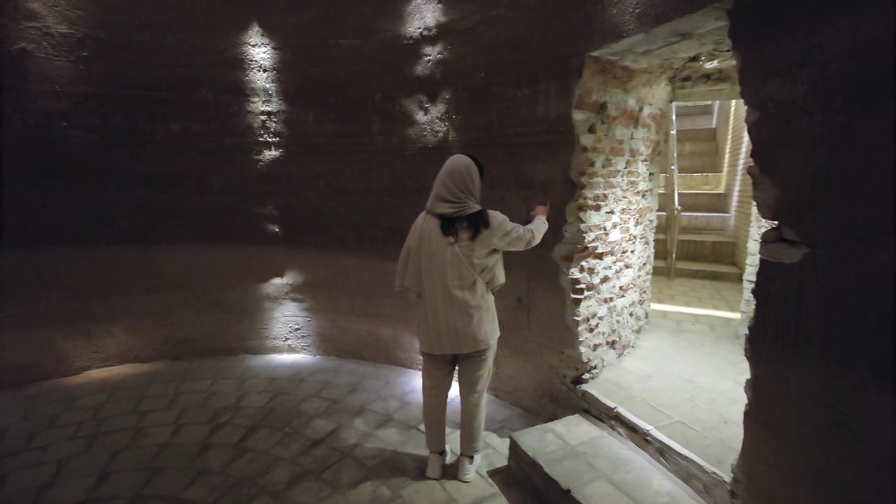 Donna che esplora un'antica camera sotterranea in pietra
