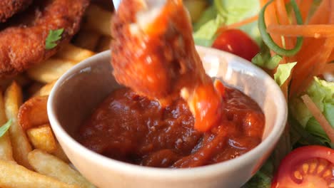 close up of chicken wings being dipped in ketchup