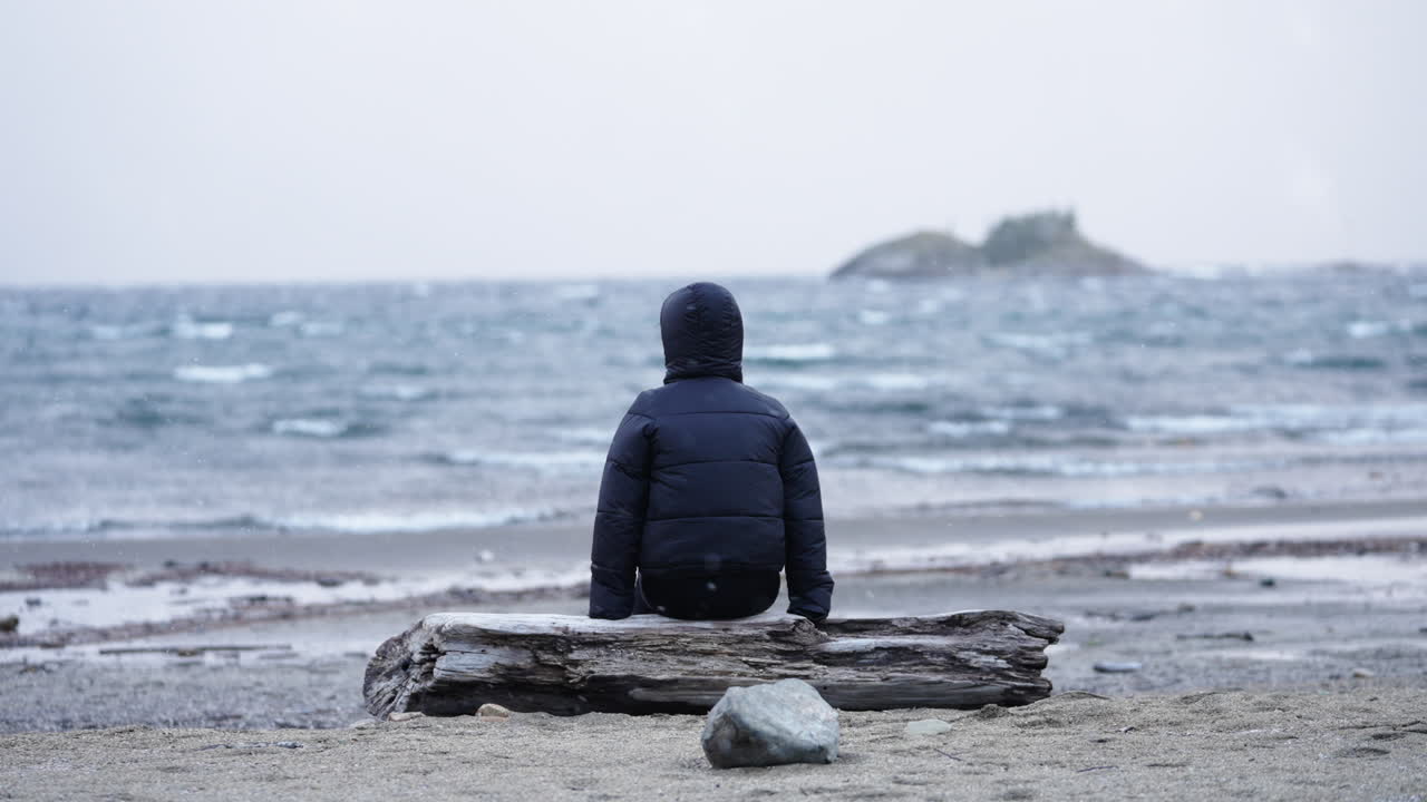 Person sitting alone by remote cold lakeshore, Reflecting in solitude, Patagonia, Argentina