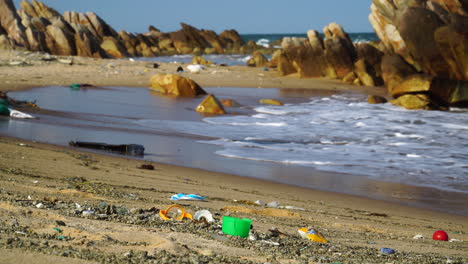 beach polluted with plastic ocean trash, tide waves rolling onto shore