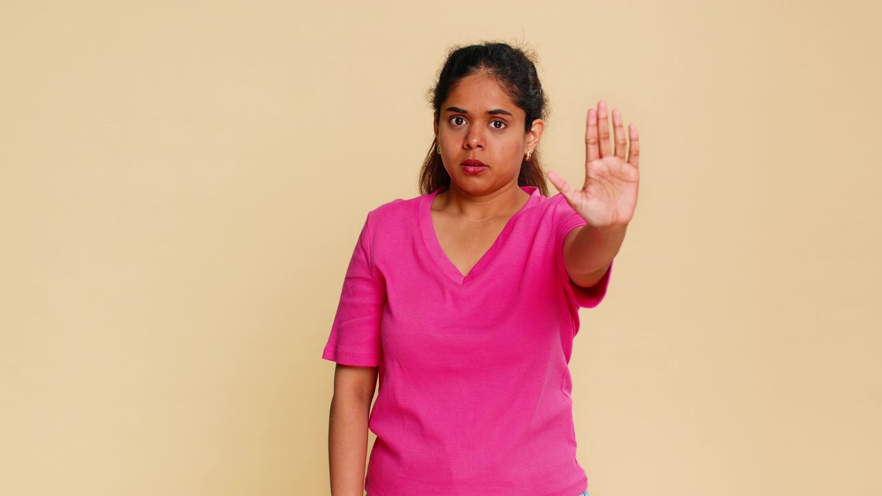 Indian woman raising open palm in stop gesture looking seriously at camera expressing prohibition