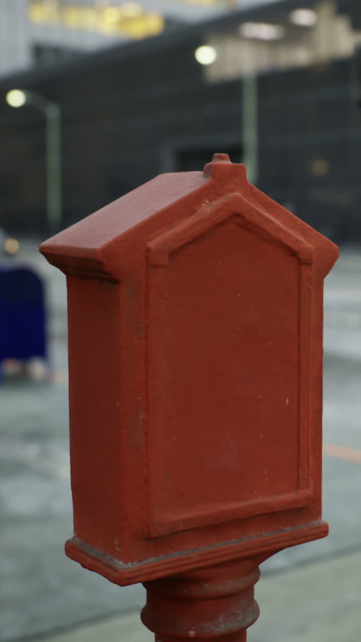 Una cassetta della posta rosso vivo si erge su una strada in un'area urbana durante il giorno.