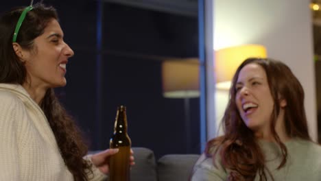 two female friends at home or in bar celebrating at st patrick's day party drinking alcohol and catching popcorn in mouth