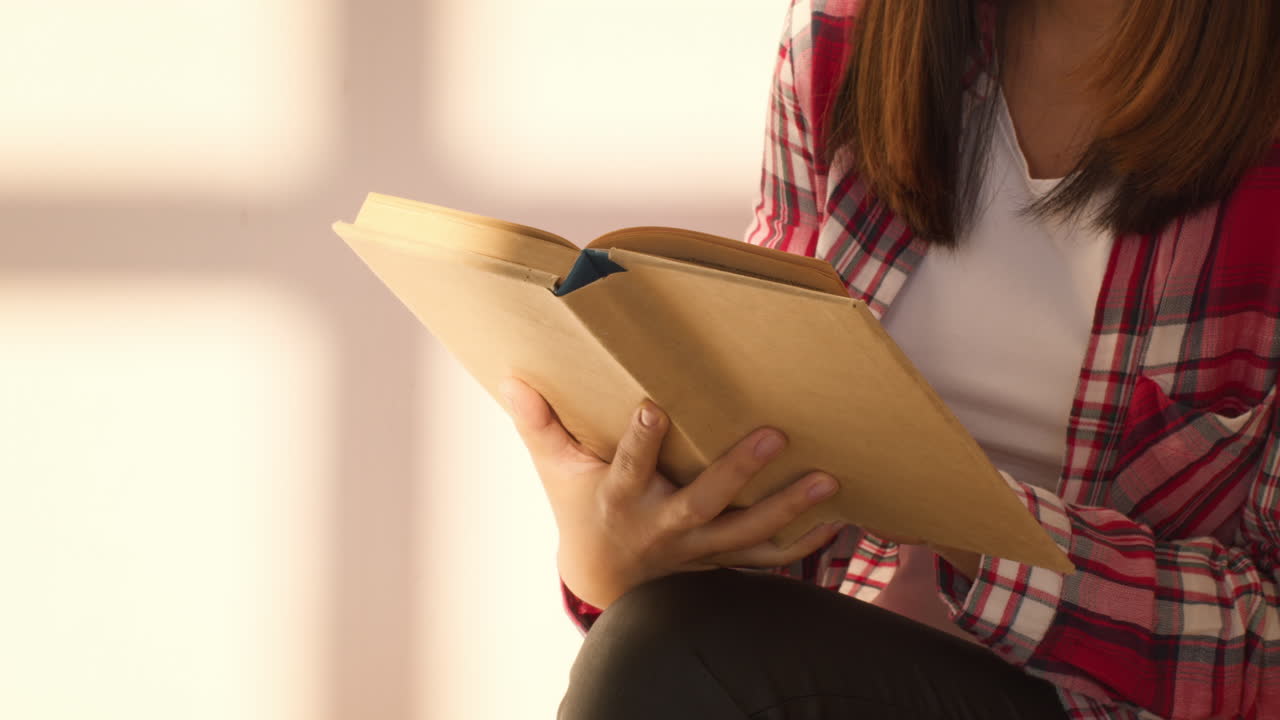 mujer leyendo un libro junto a la ventana