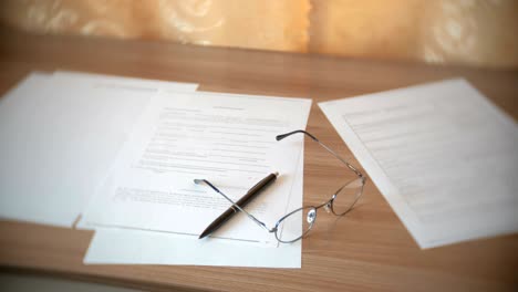 glasses, papers documents and pen on the table.