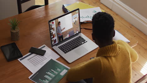 estudiante afroamericana usando una computadora portátil en una videollamada con un profesor masculino
