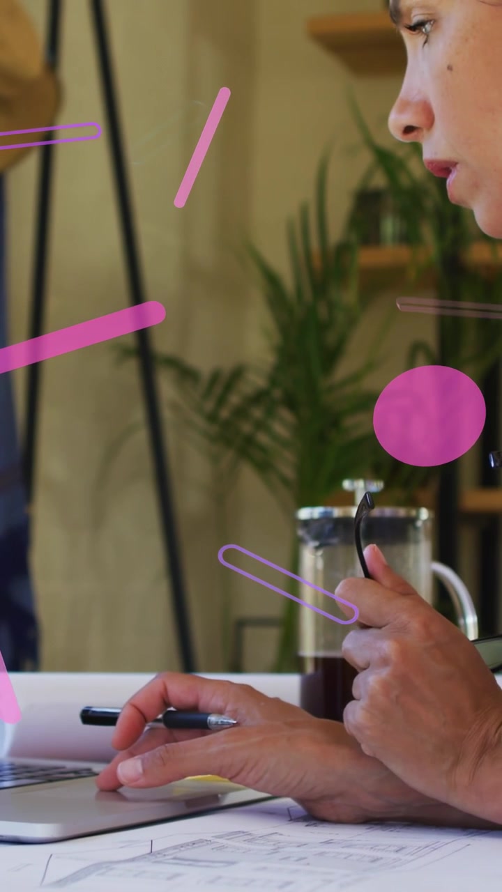 Video verticale: Designer che usa uno stilo, forme rosa che fluttuano mentre esamina i piani e si sposta a destra.