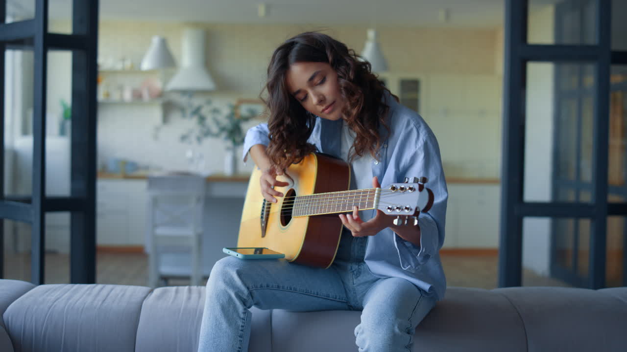 mujer tocando la guitarra acústica en casa