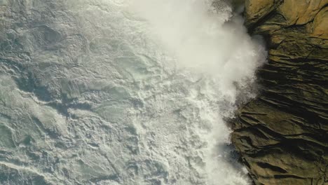 White-Foamy-Waves-Hit-Rocky-Coastline-During-Sunrise