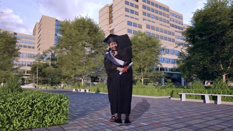 cuerpo lleno de estudiantes asiáticas graduadas con gorras y túnicas con diplomas sonriendo y abrazándose frente a un magnífico edificio universitario