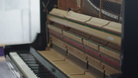 inner mechanism of an open wall piano on a pull focus shot