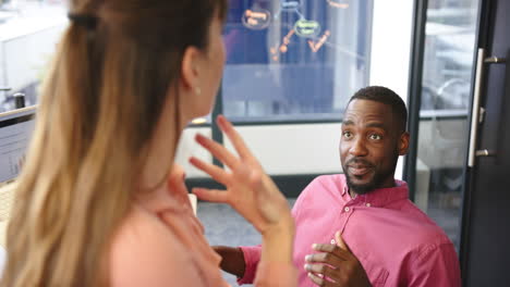 smiling african american man in office talking with colleague, engaging in conversation