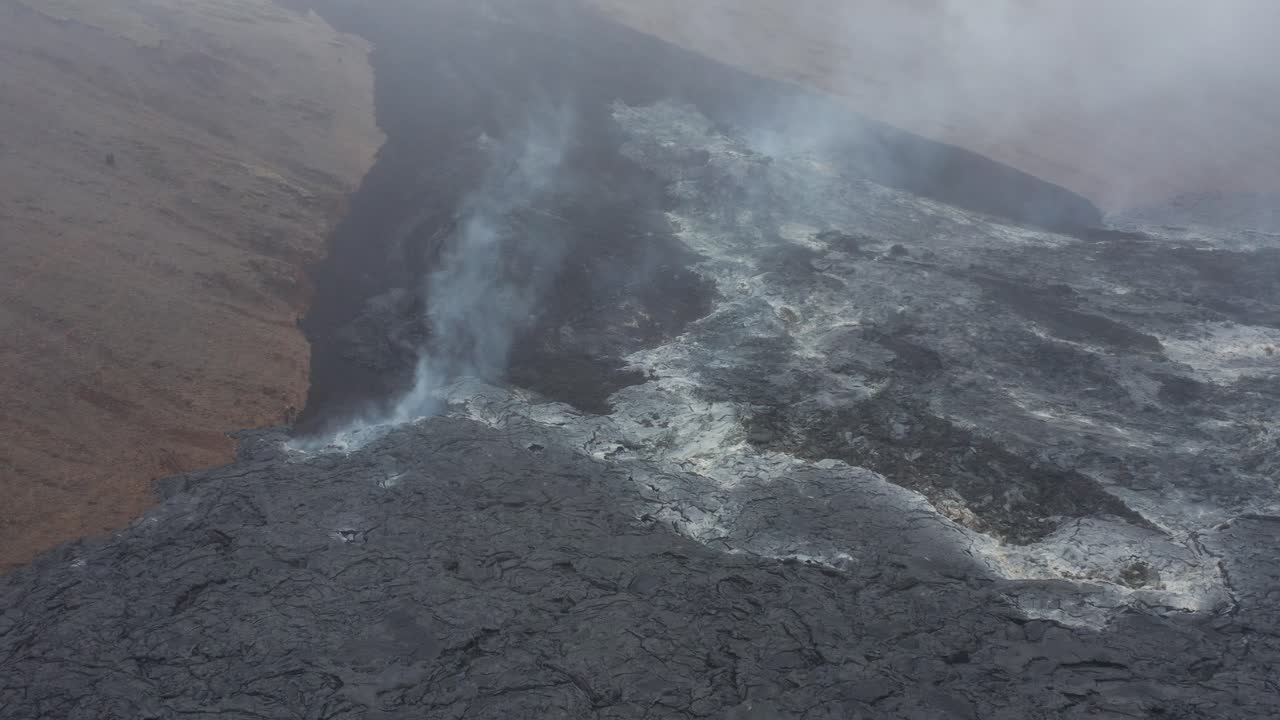 Steam rises from hot basalt field during cloudy day in Iceland, aerial