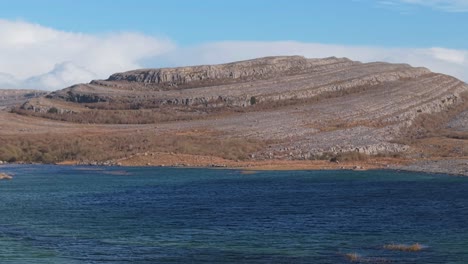rocky limestone landscape with layered formations by a blue lake in the burren, ireland