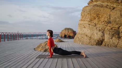 woman practicing yoga on a wooden platform by the sea