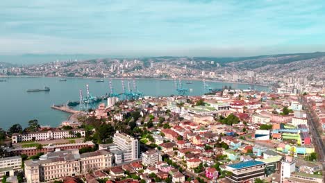 aerial parallax of colorful neighborhood in playa ancha hill, valparaã­so sea port and hillside city in background, chile