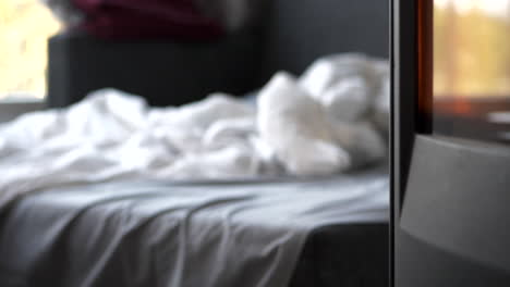 unmade bed next to fireplace. focus on foreground