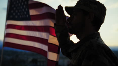 silhouette of a soldier salutes in front american flag at sunset memorial day
