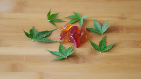 slow motion hand picking out cbd gummy from candy pile surrounded by marijuana leaves