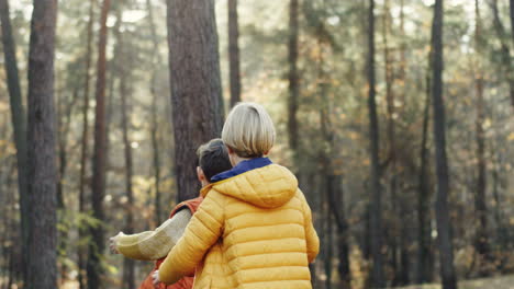 rear view of two little boys running in the forest, one escaping and another trying to catch him