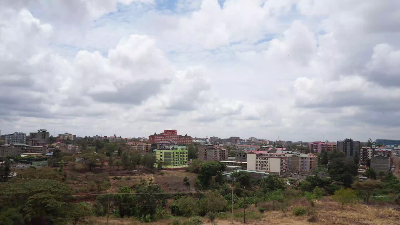 Ombre di nuvole passano sui sobborghi di Nairobi in un paesaggio arido ai margini di una foresta secca con condomini.
