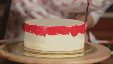 decorating a vanilla cake with red frosting