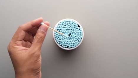 mano sosteniendo un botón de algodón sobre un recipiente de algodones