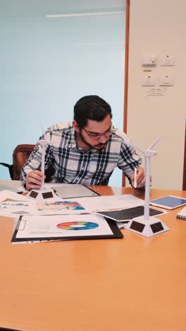 male engineer holding a miniature wind turbine model