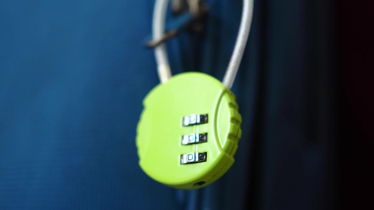 Primo piano di un lucchetto a combinazione verde su una valigia blu