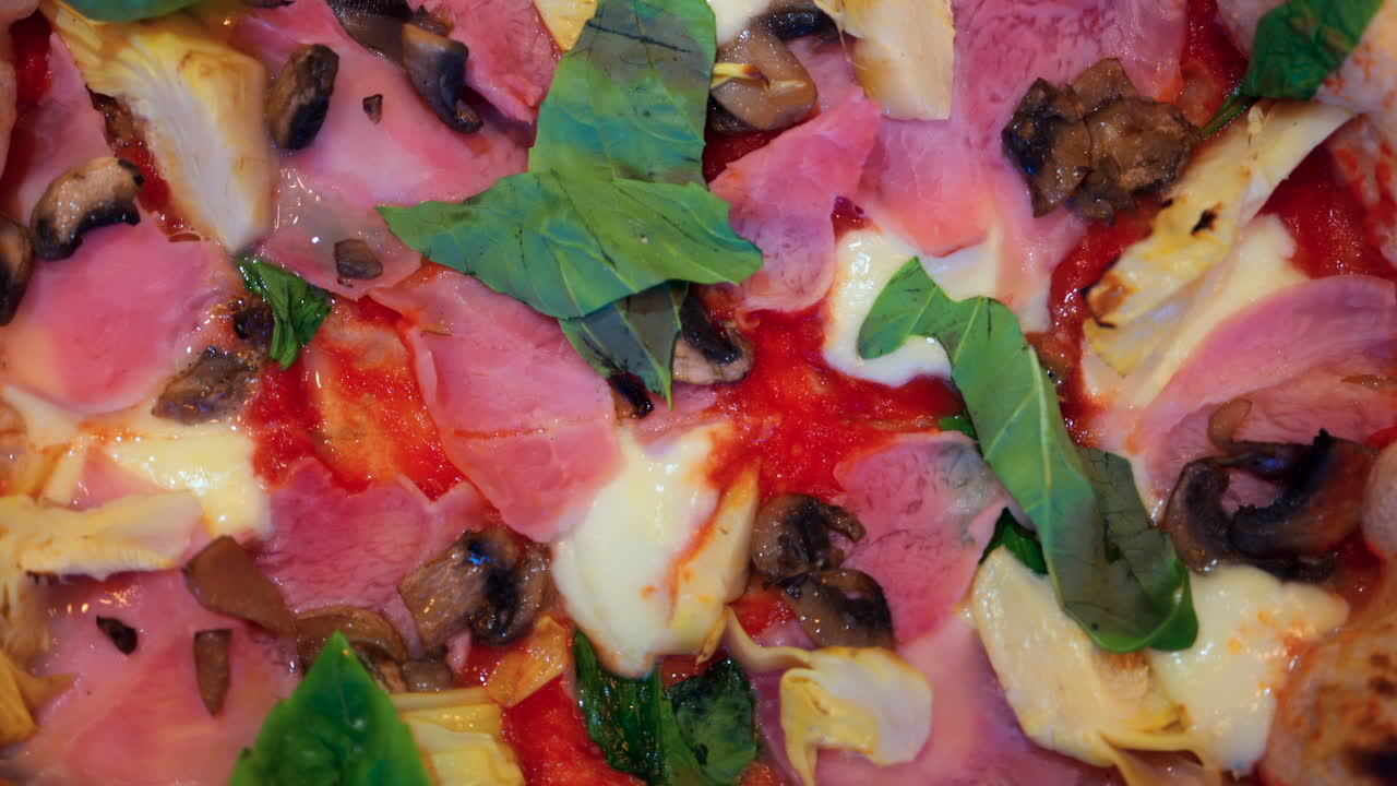 Close up of pizza with artichoke, ham, mushrooms and basil