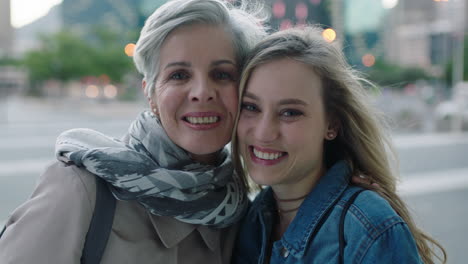 portrait of mother and daughter embrace looking at camera smiling happy stylish independent women in urban city background