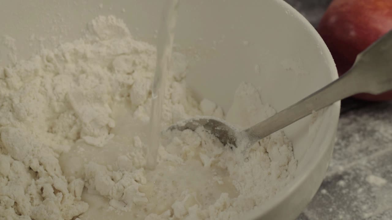 Adding water to dough in a bowl close up shot