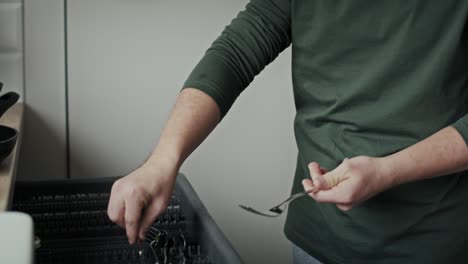 hombre adulto con síndrome de down cargando lavadora de platos en casa por sí mismo.