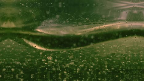 abstract of green and golden bubbles slowly floating in liquid with raindrops