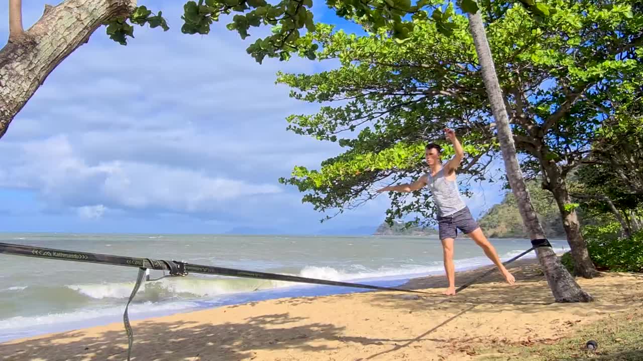 macho adulto practicando en slackline en trinity beach en cairns