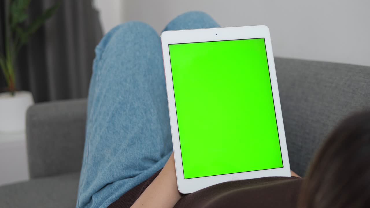 manos sosteniendo tableta vertical con pantalla verde y maqueta de tecla de croma