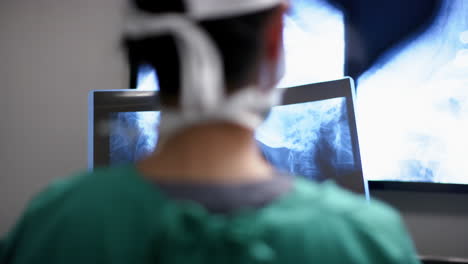 cirujana biracial mirando con escáneres de rayos x en el quirófano del hospital, en cámara lenta